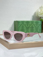 Gucci sunglasses, pink frames with dark lenses and gold GG logo.