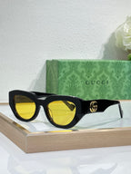 Gucci sunglasses, black frames with yellow lenses and gold GG logo.