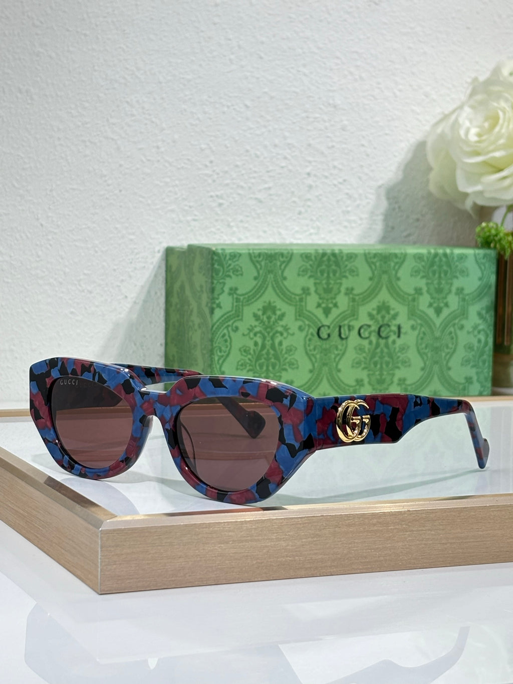 Gucci sunglasses, blue patterned frames with dark lenses and gold GG logo.