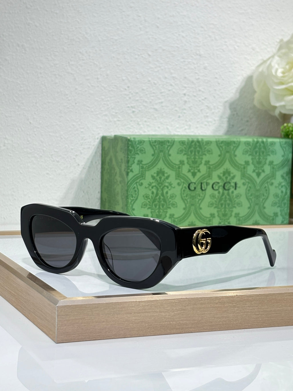 Gucci sunglasses, black frames with dark grey lenses and gold GG logo.
