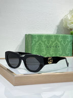 Gucci sunglasses, black frames with dark grey lenses and gold GG logo.