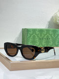 Gucci sunglasses, dark tortoiseshell frames with brown lenses and gold GG detail.