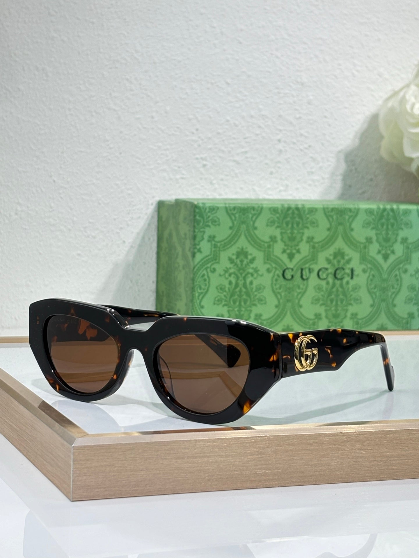Gucci sunglasses, dark tortoiseshell frames with brown lenses and gold GG detail.