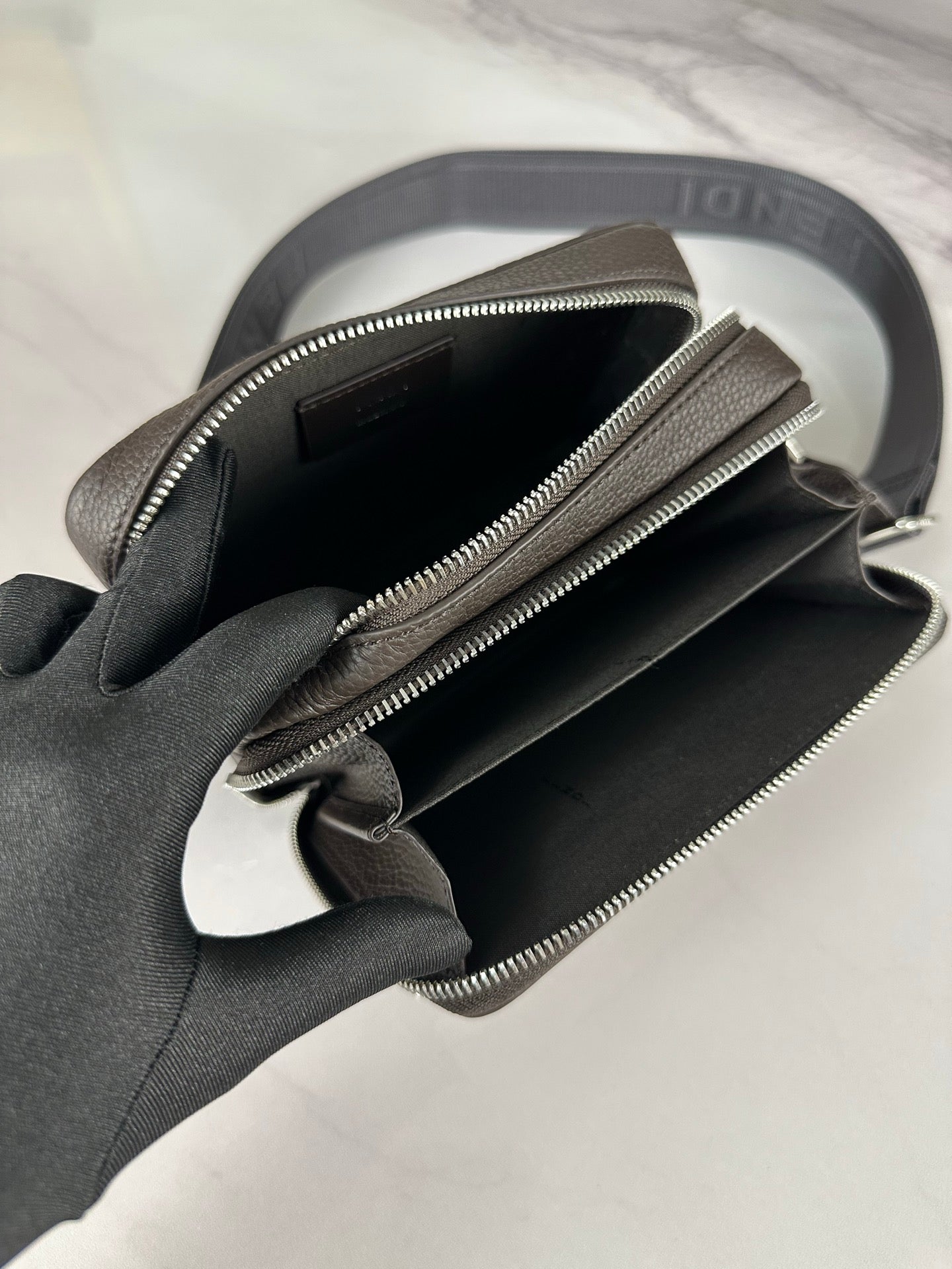 Fendi crossbody bag open view showing dark interior and two zip compartments with hardware.