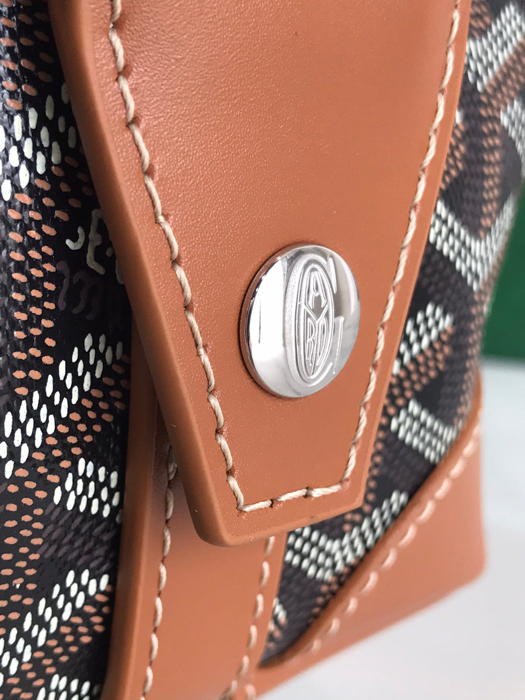 Brown leather corner patch with round silver emblem and stitched trim