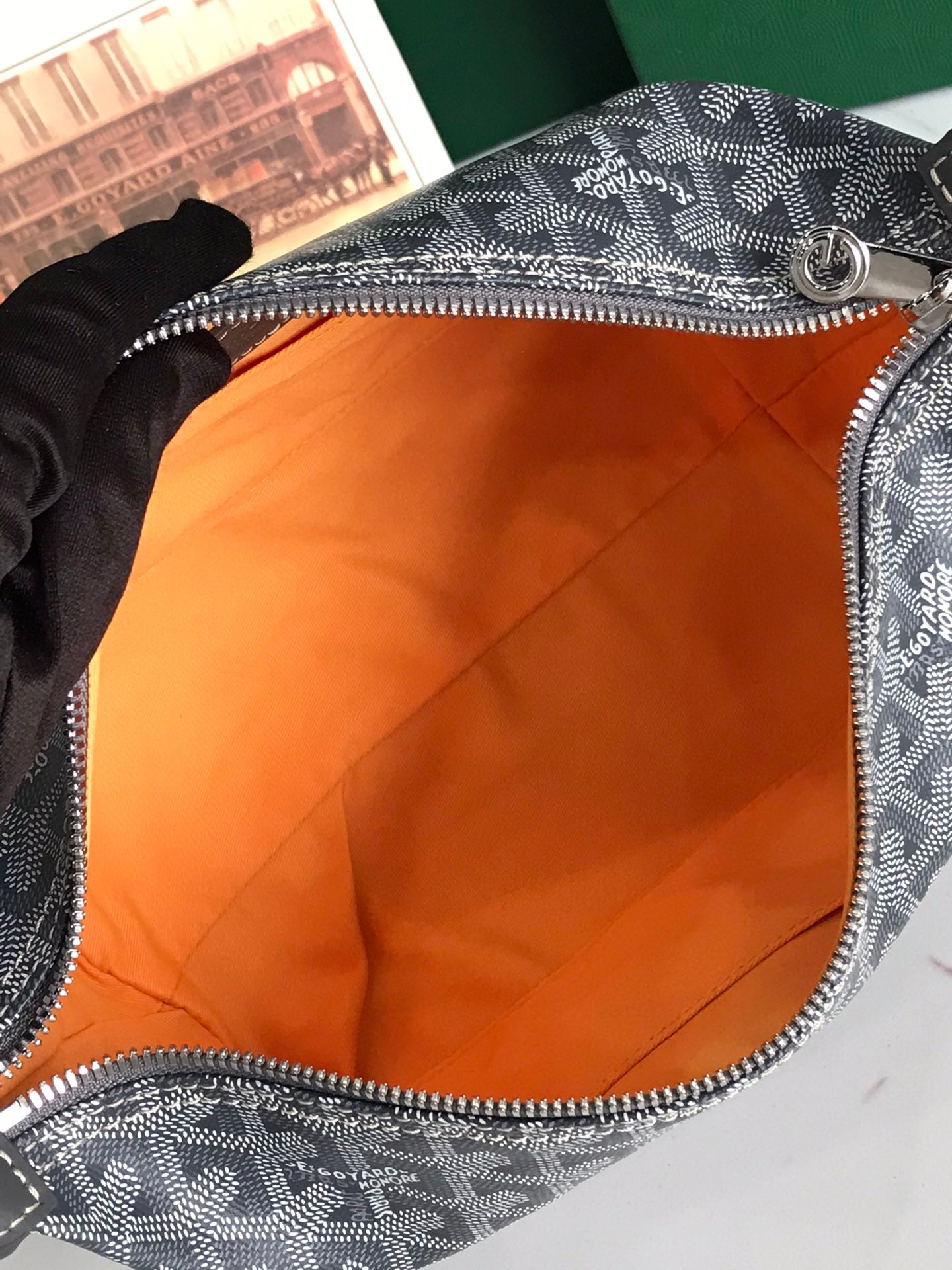 Goyard bag open top with orange fabric lining and zippered opening on monogram canvas