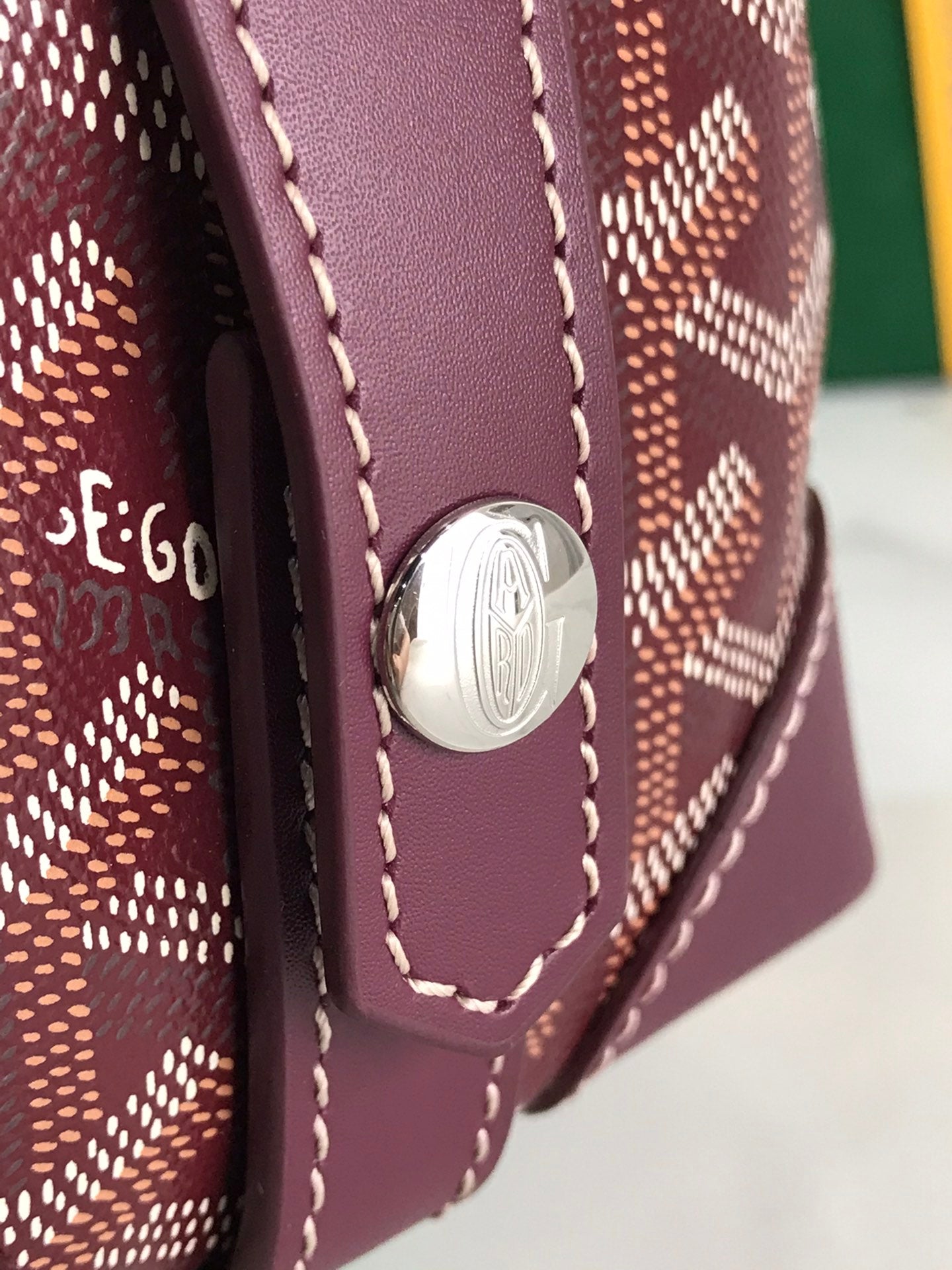 Leather end panel with round emblem on patterned bag, stitched details