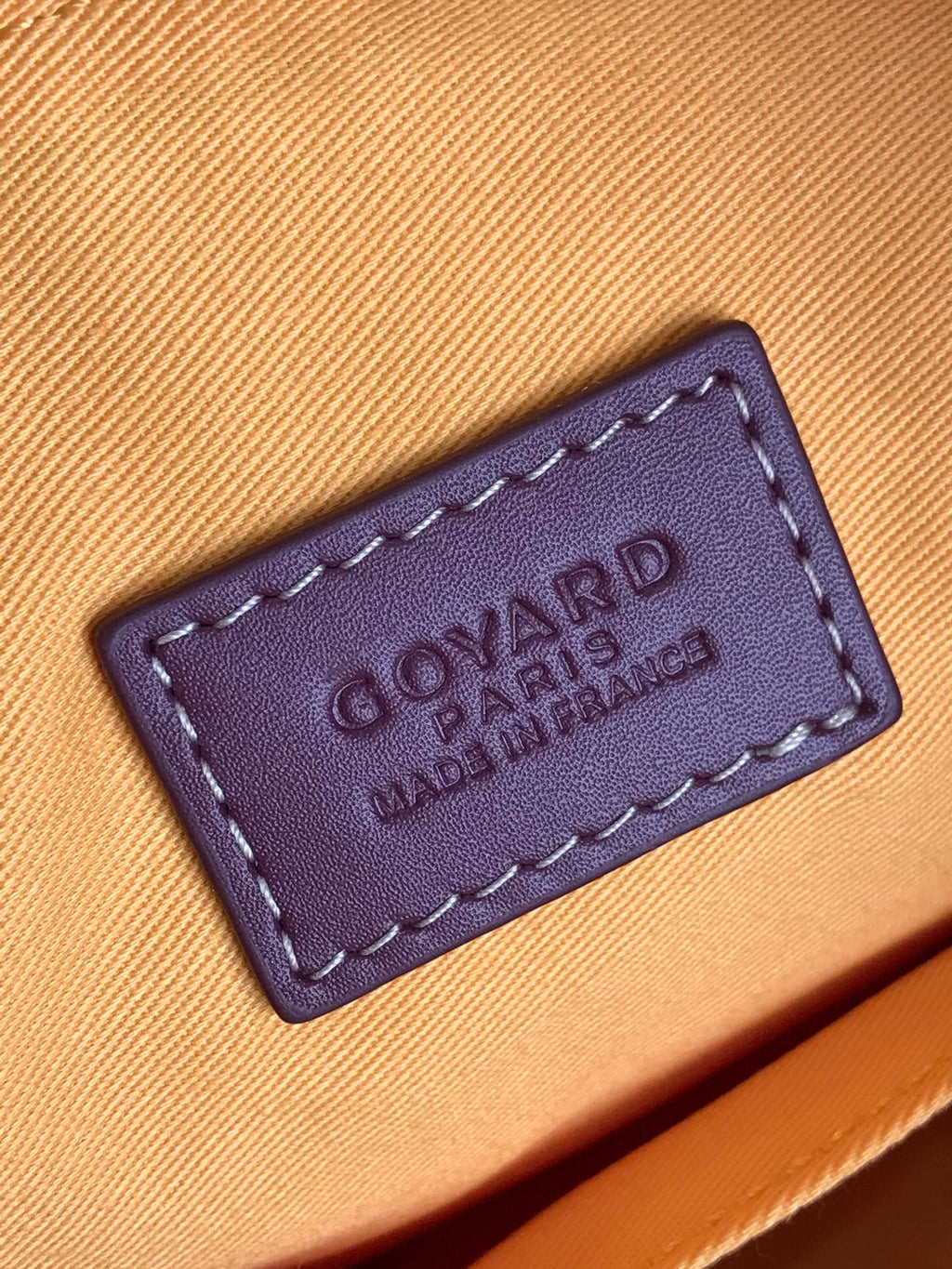 Leather brand label on beige lining inside handbag, embossed text