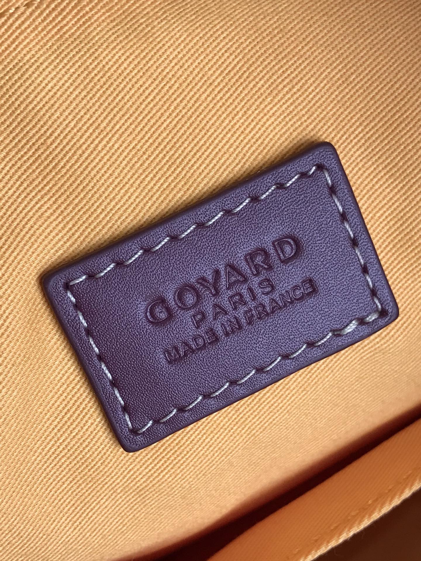 Leather brand label on beige lining inside handbag, embossed text