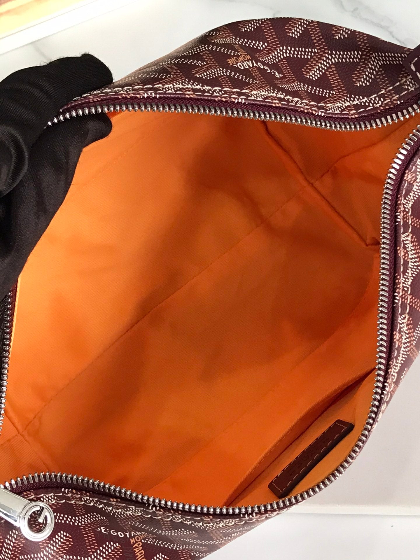 Open handbag interior with smooth orange lining and zippered edge