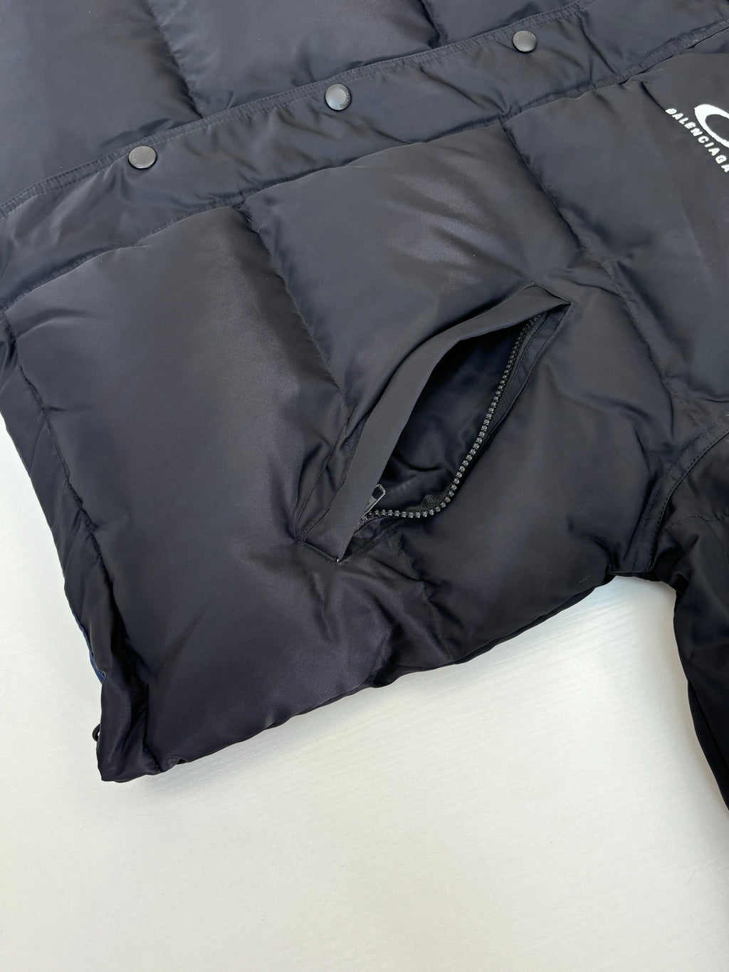 Balenciaga long puffer jacket, dark fabric close-up with zip pocket detail