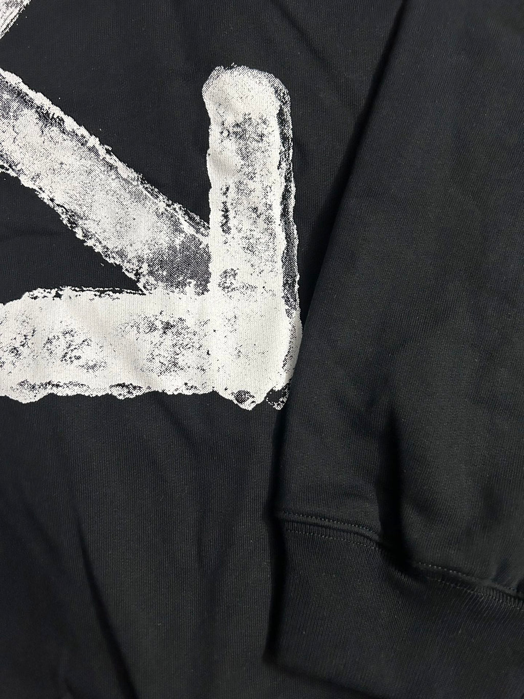 Black hoodie with distressed white arrow logo detail and ribbed sleeve cuff