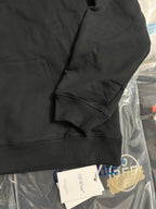Black pullover hoodie sleeve with kangaroo pocket seam and ribbed cuff