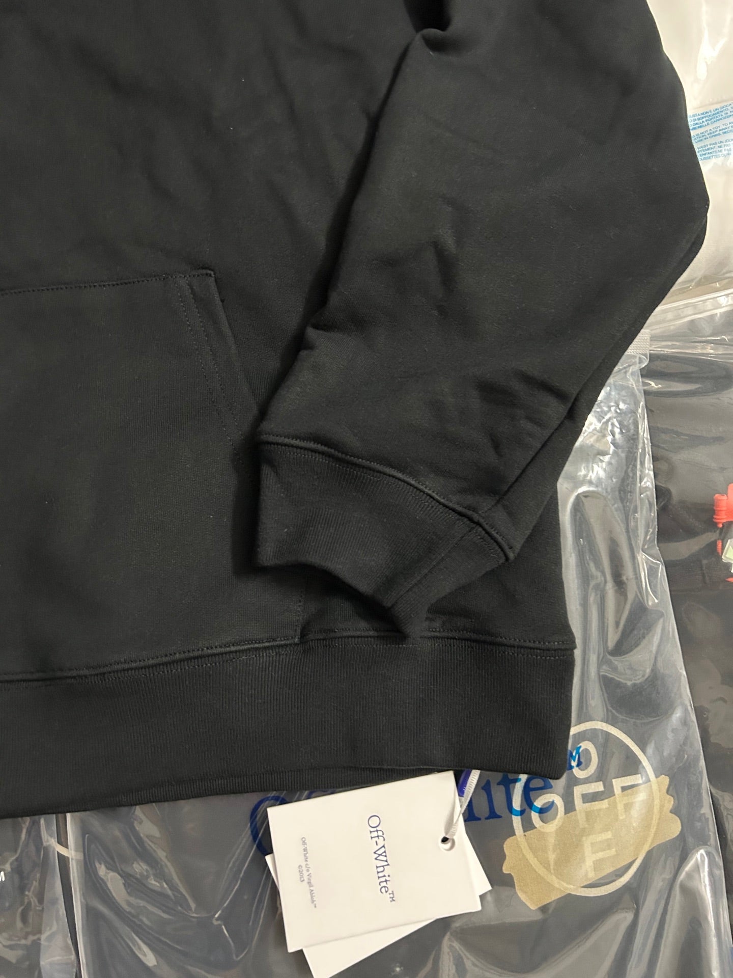 Black pullover hoodie sleeve with kangaroo pocket seam and ribbed cuff