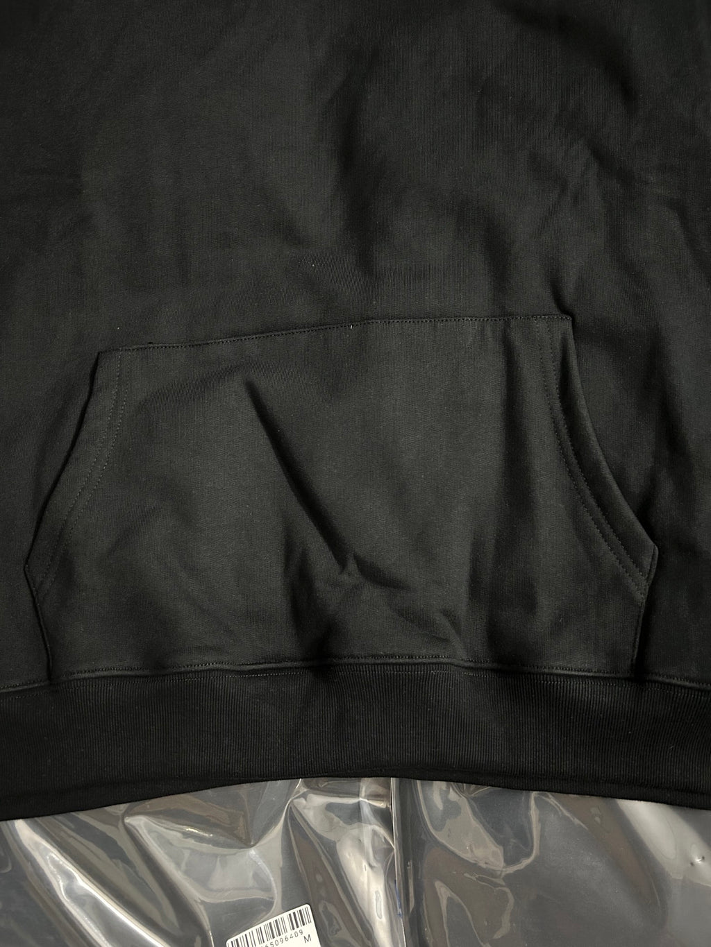 Black hoodie hem with front kangaroo pocket seam and gathered fabric
