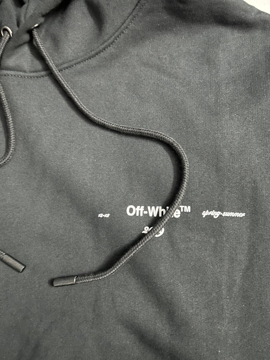 Off-White black hoodie chest close-up with small logo and drawcords