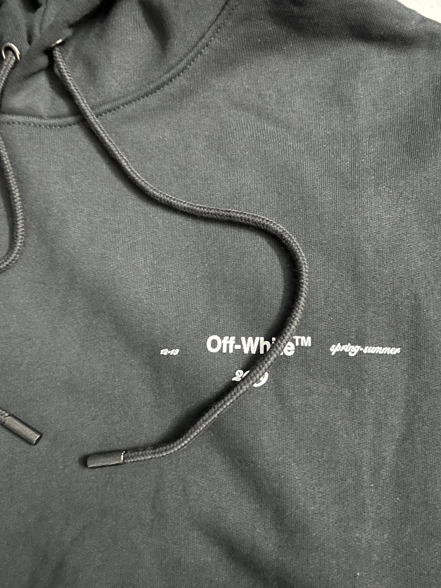 Off-White black hoodie chest close-up with small logo and drawcords