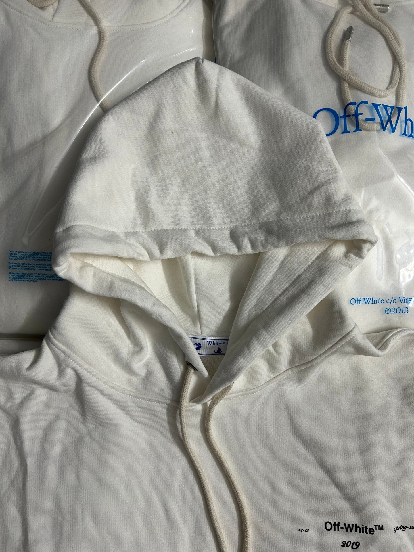 Off-White white hoodie, close view of hood and drawstring with blue graphic accents