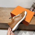 Brown Hermes unisex sneaker with white laces and black heel strap, front view