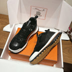 Hermes unisex sneakers in black, one with textured outsole, displayed in shoe box