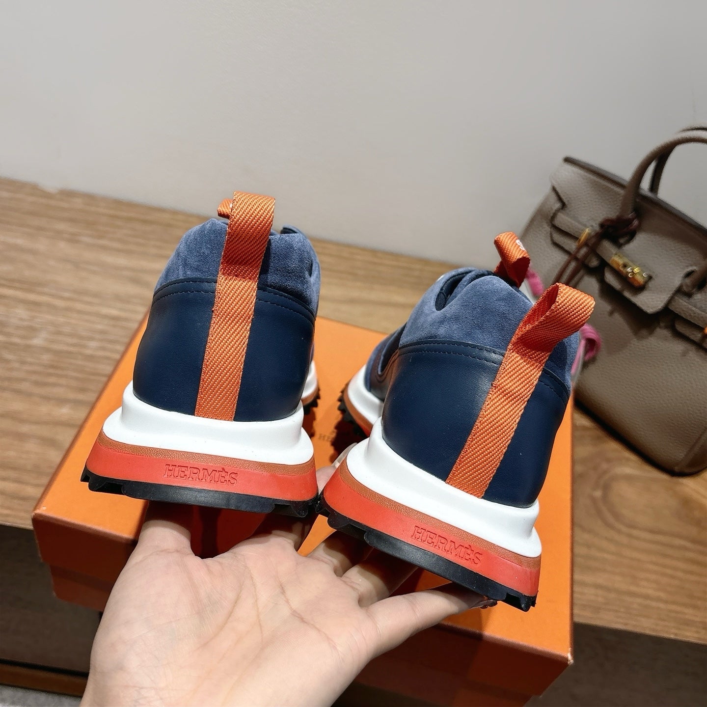 Hermes unisex sneakers heel view, navy blue with orange strap and white/red sole