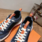Hermes unisex sneakers close-up, navy blue knit panels with white laces and orange tab