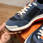 Hermes unisex sneaker close-up, navy blue suede and mesh with white laces and orange trim