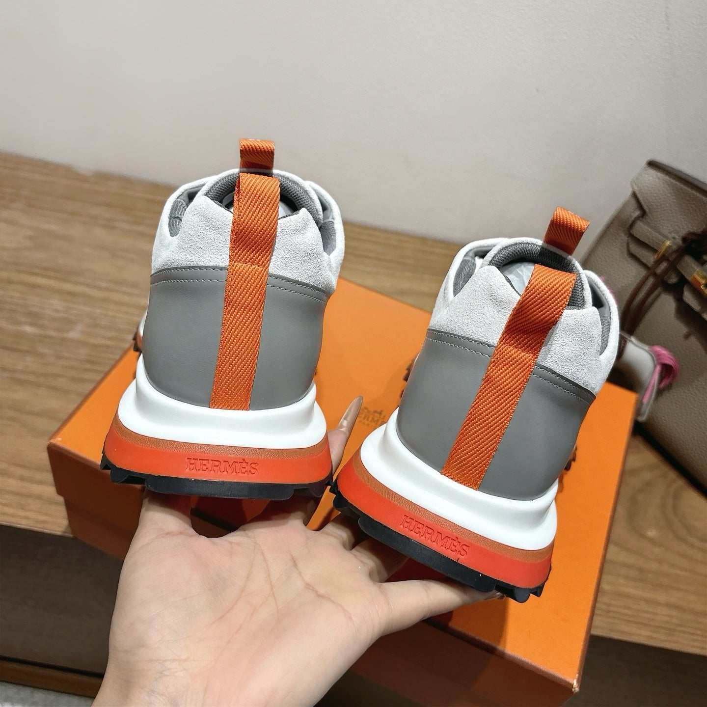 Hermes unisex sneakers heel view, gray and white with orange heel tab and stripe