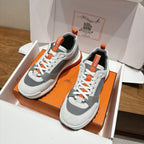 Hermes unisex sneakers in open box, white leather with gray panels and orange accents