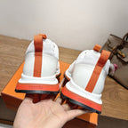 Back view of white sneakers with orange heel pull tabs on orange box