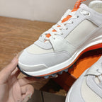 White low-top sneaker close-up with orange laces and orange-edged sole