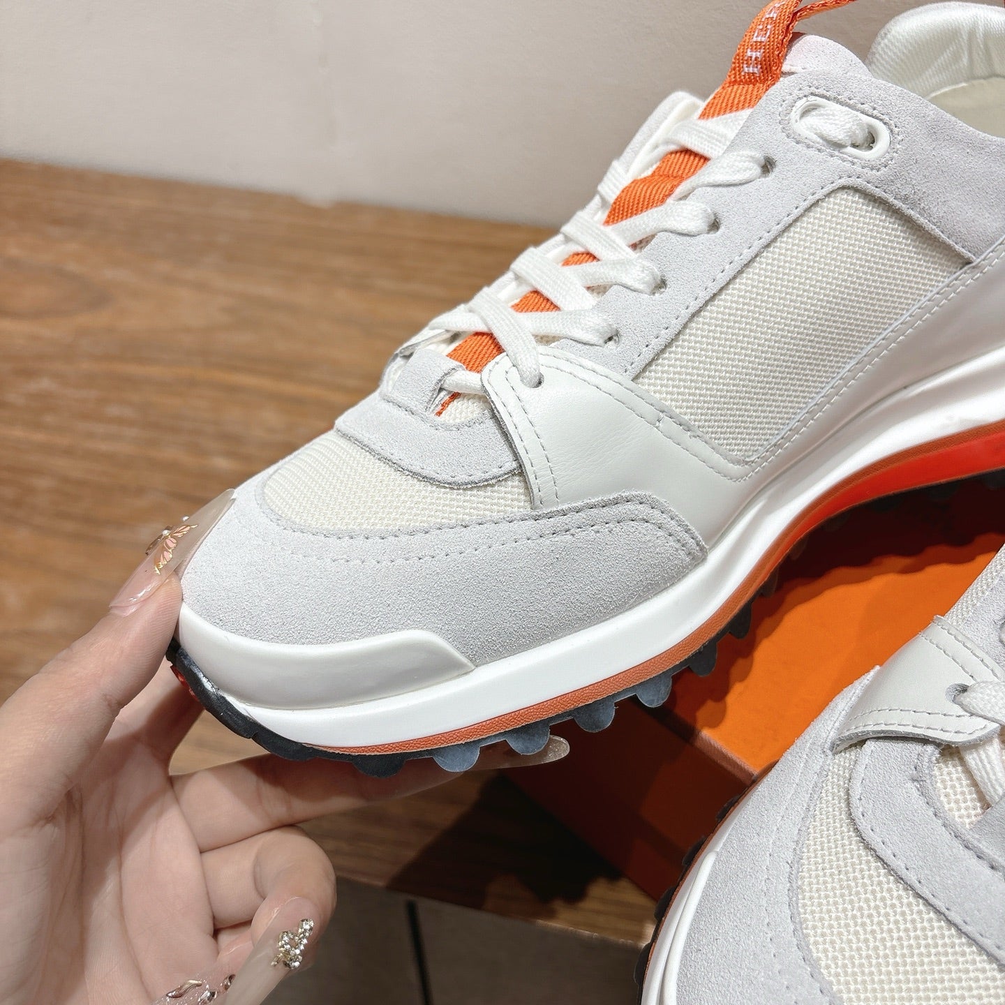 White low-top sneaker close-up with orange laces and orange-edged sole