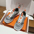 Grey sneakers in orange-and-white box, orange heel tab and white lace-up visible