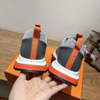 Back view of grey sneakers with orange heel straps and white midsoles