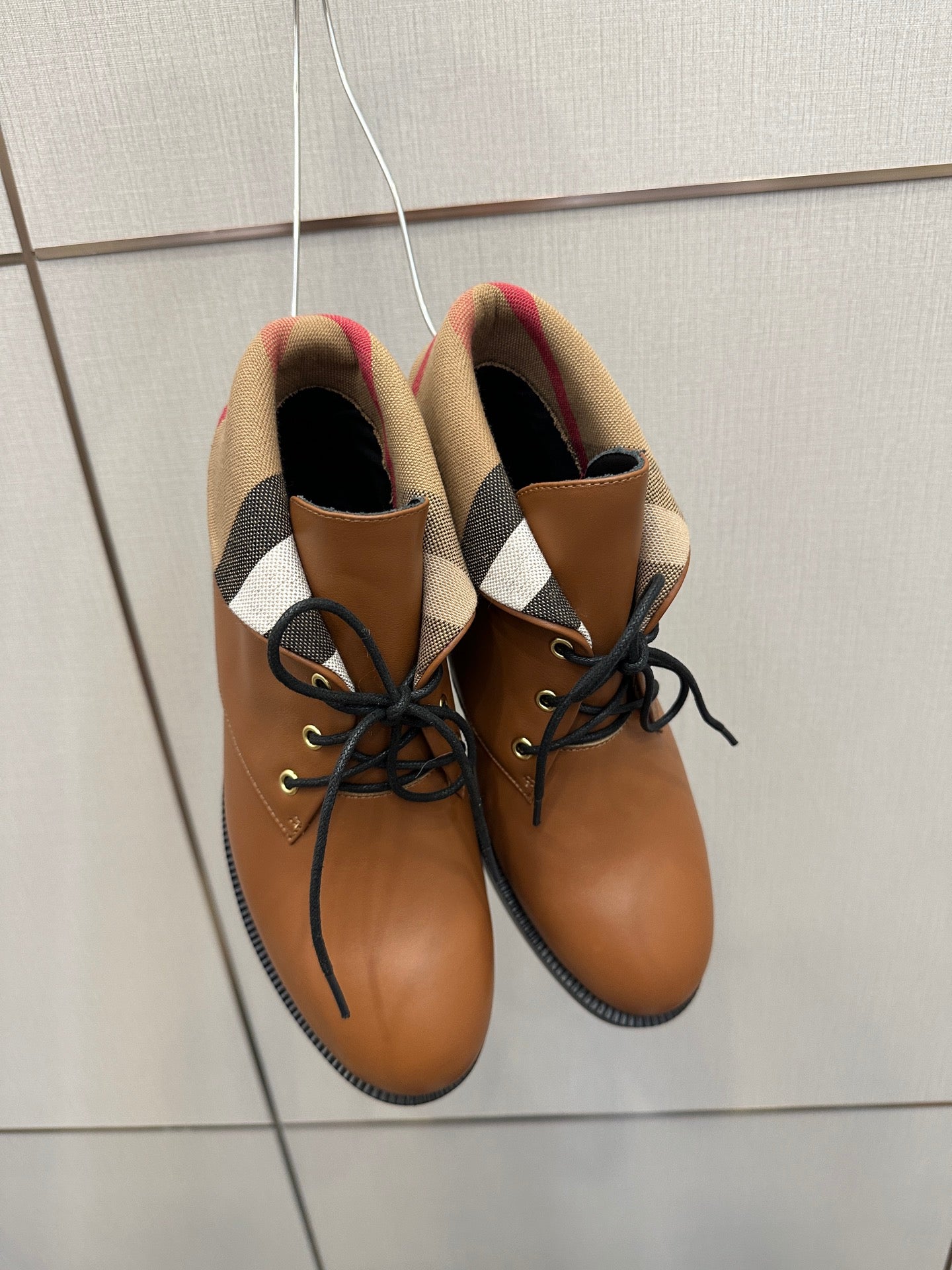 Close-up of tan lace-up shoes with black laces and plaid fabric-lined collar