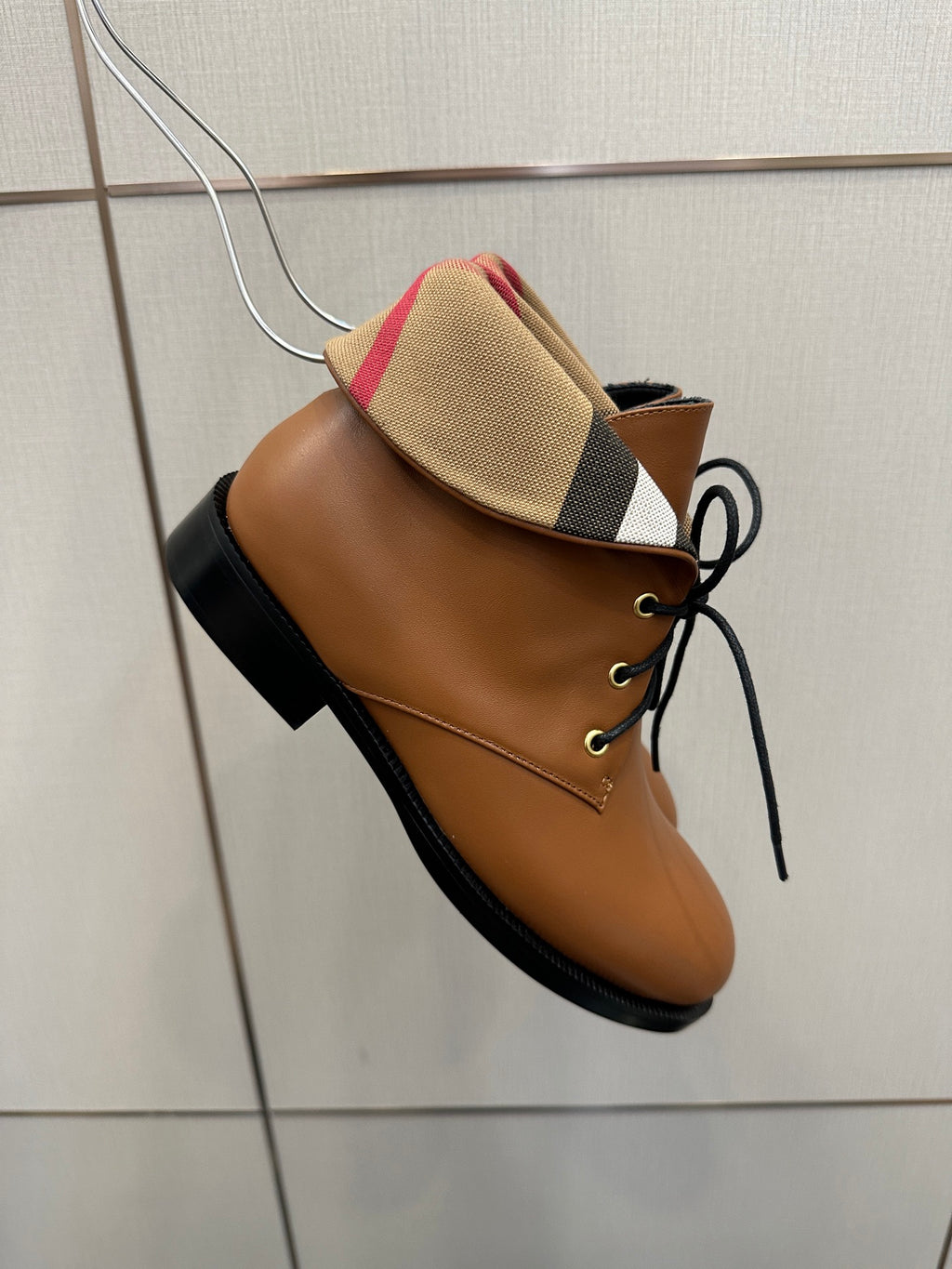 Side view of tan lace-up shoe with plaid collar and black sole