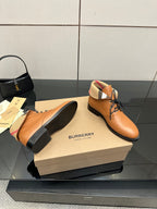 Tan lace-up shoes with black soles and plaid lining at the ankle