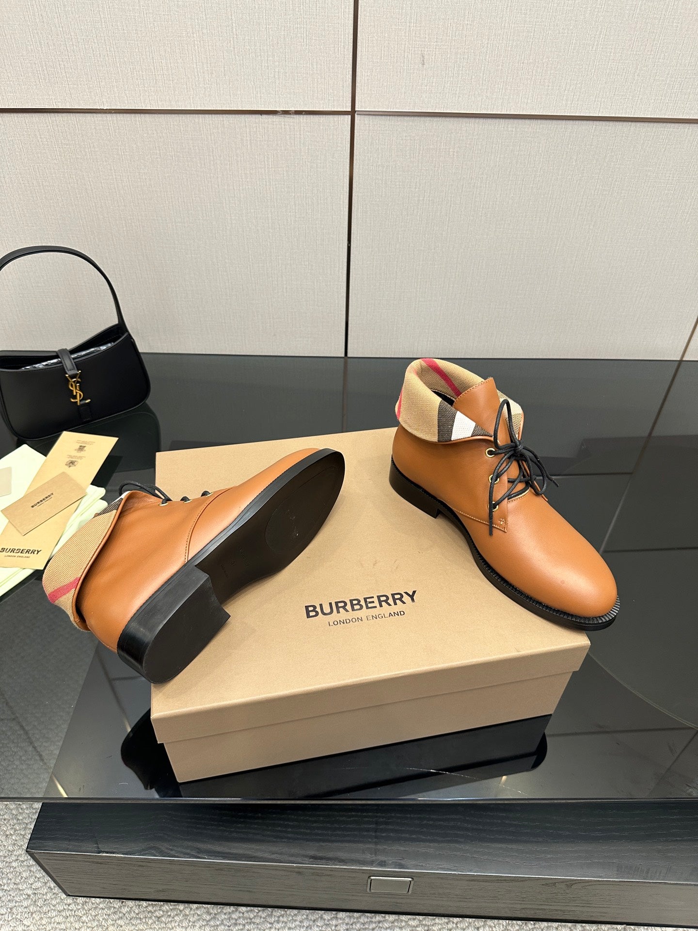 Tan lace-up shoes with black soles and plaid lining at the ankle