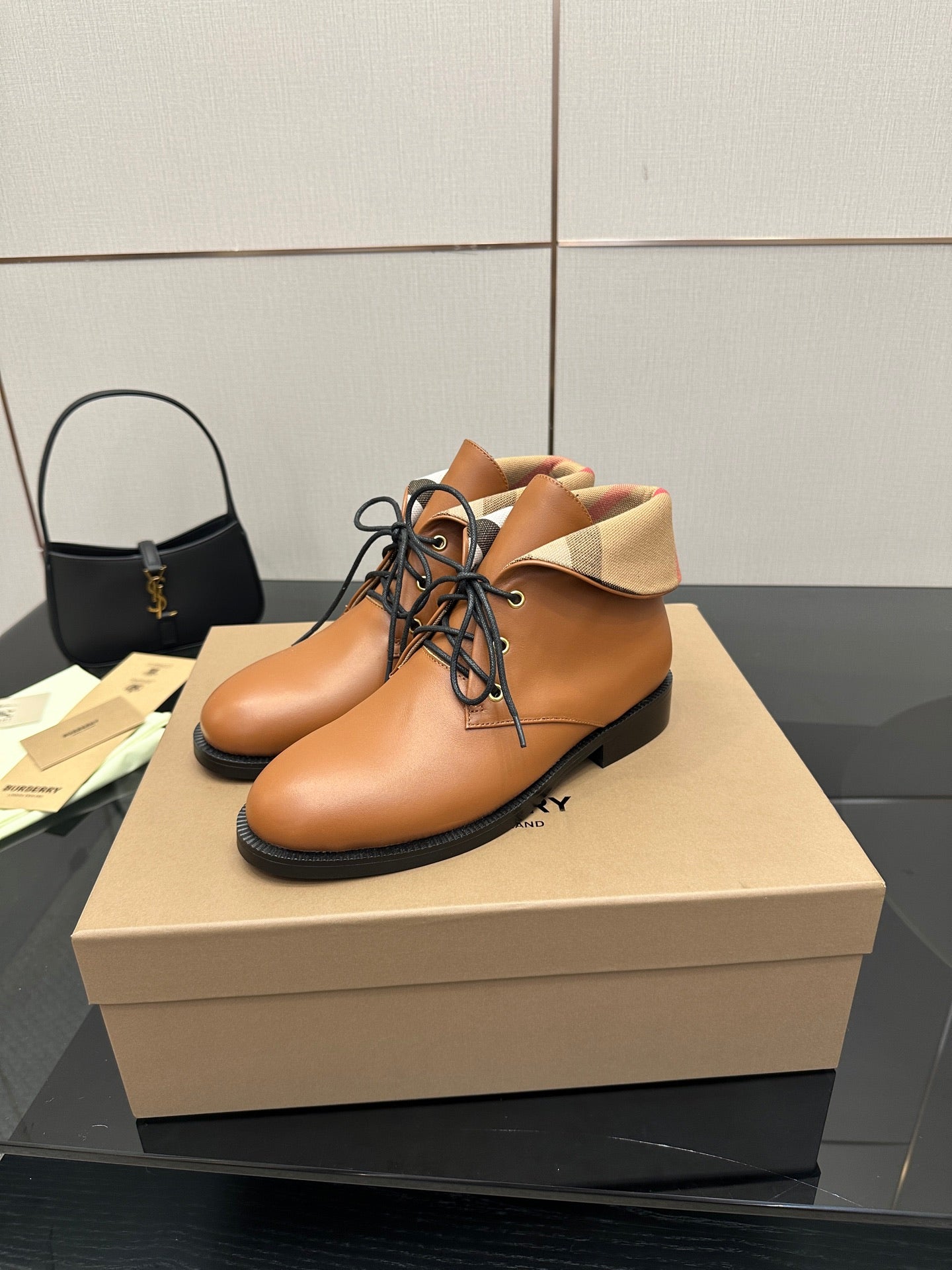 Tan lace-up ankle shoes with black rubber sole and plaid cuff detail