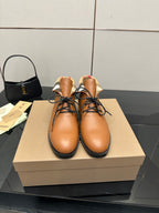 Tan lace-up shoes with black soles and plaid fabric at the ankle collar