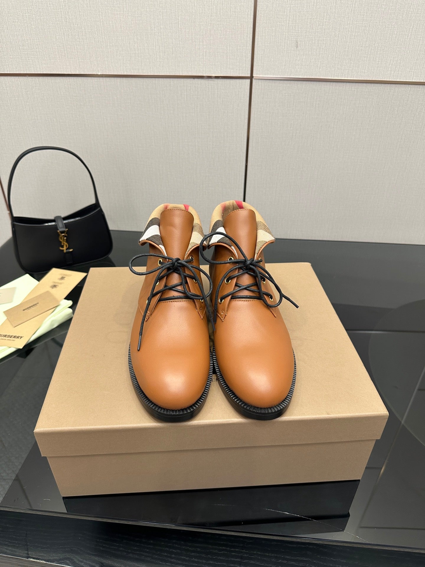 Tan lace-up shoes with black soles and plaid fabric at the ankle collar