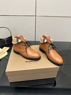 Pair of tan lace-up shoes with black soles and plaid trim around the collar