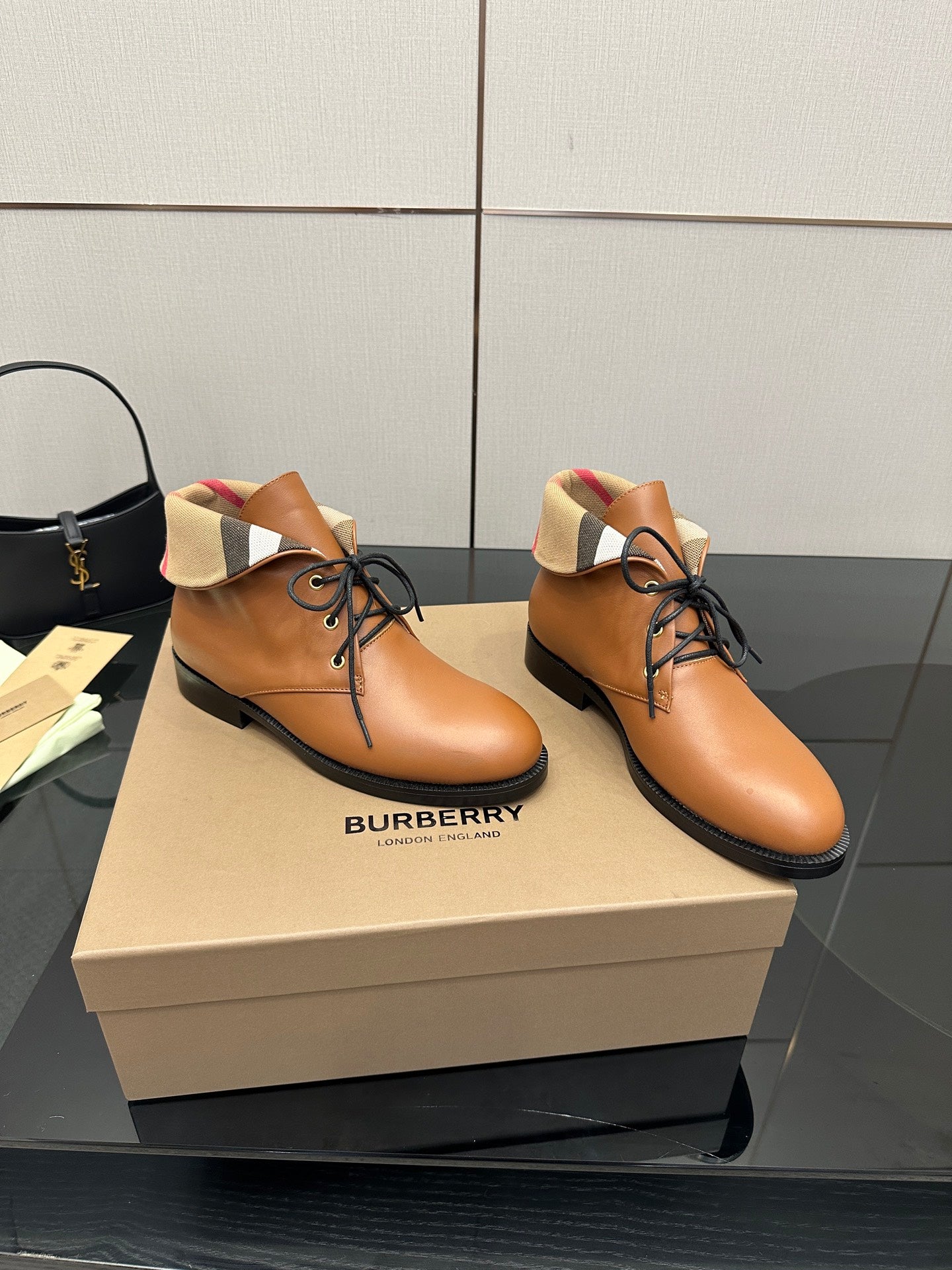 Pair of tan lace-up shoes with black soles and plaid trim around the collar