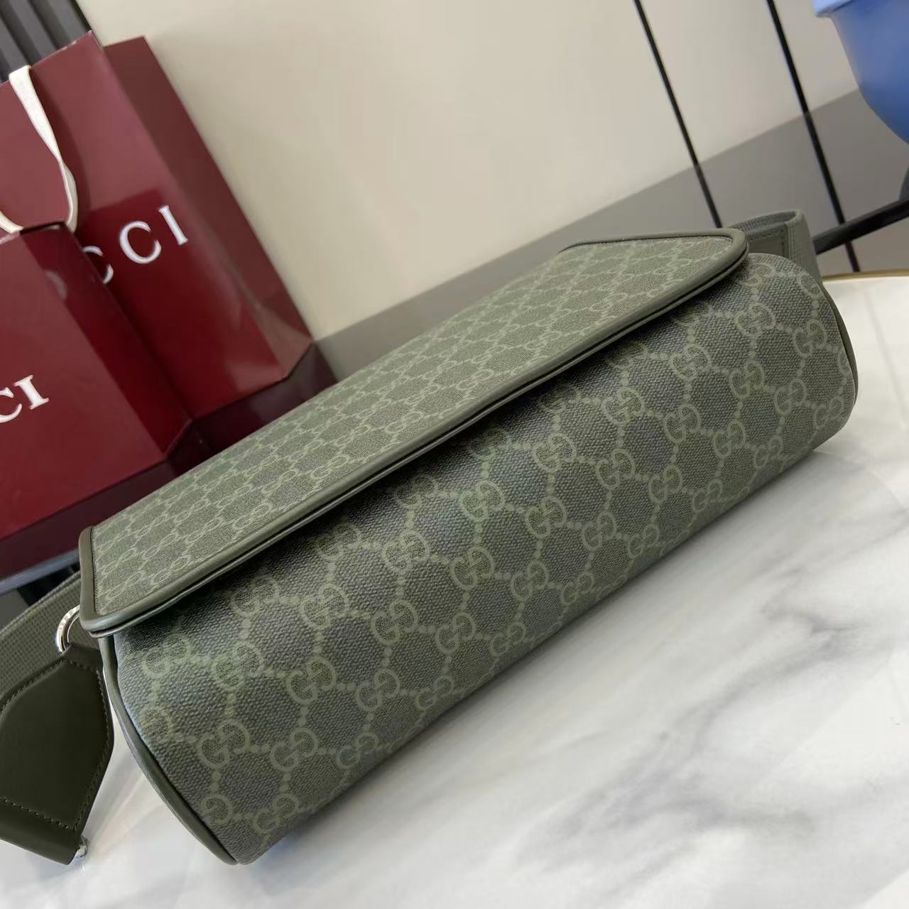 Gucci GG monogram shoulder bag lying flat, olive green canvas with flap