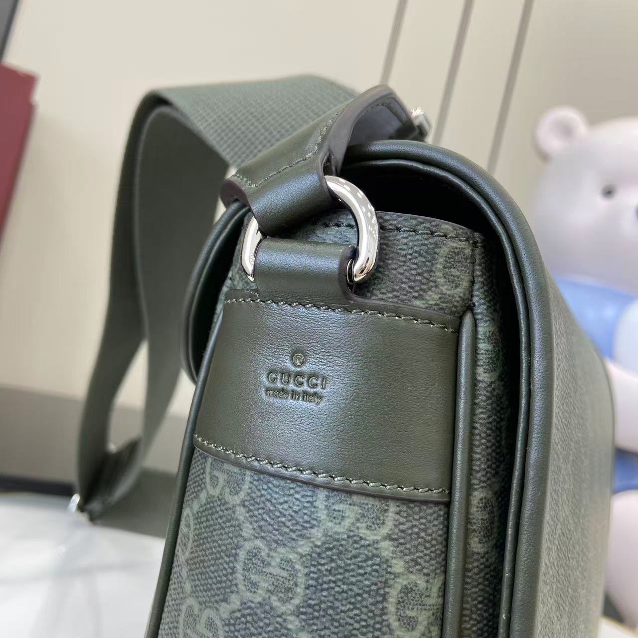 Gucci bag top corner with ring hardware, green leather trim, and GG canvas