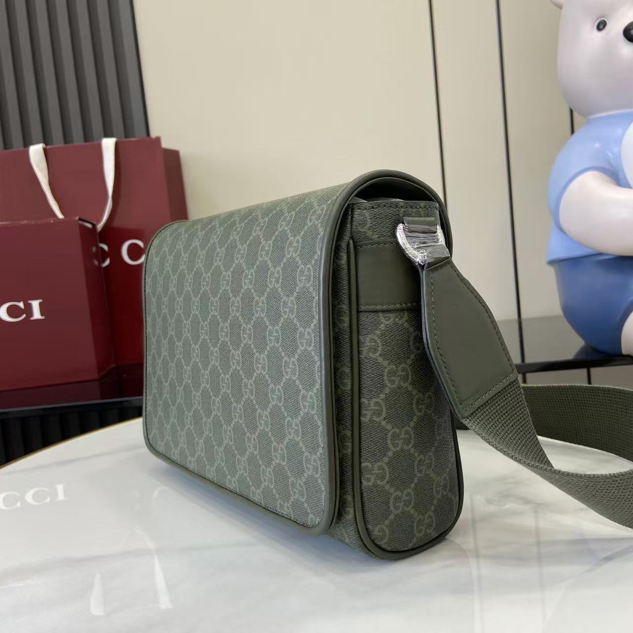 Gucci GG monogram flap bag side view with green leather trim and shoulder strap