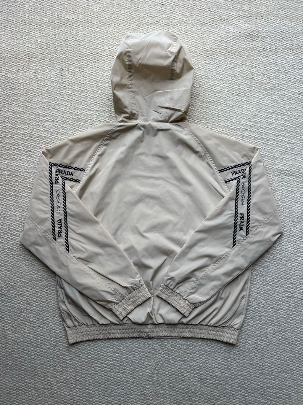 Prada hooded jacket in light beige, back view with hood and logo sleeve panels.