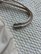 Beige hood drawstring with silver Prada logo tip on hooded jacket.