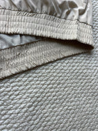 Light beige hooded jacket hem with gathered elastic cuff and stitched seam lines.