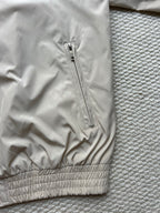 Prada hooded jacket with front zipper and ribbed elastic hem in light beige.